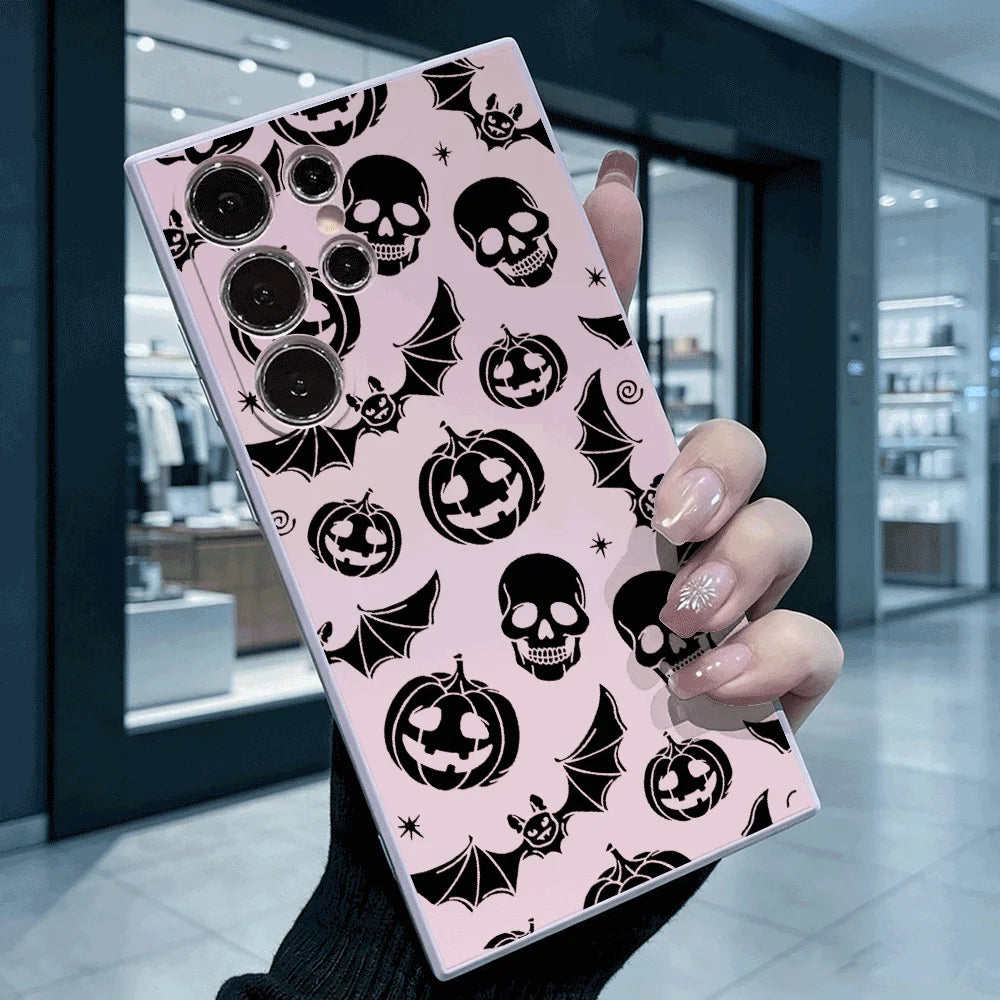 Hand hält rosafarbene Samsung-Hülle mit schwarzem Halloween-Muster aus Totenköpfen, Kürbissen und Fledermäusen, Rückansicht