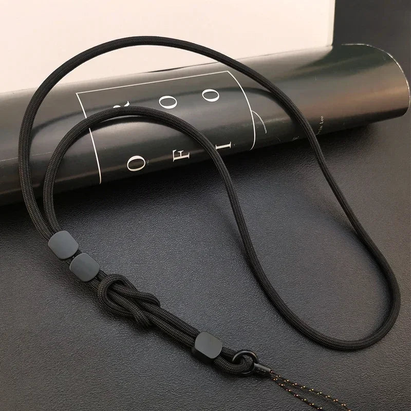 Schwarzes Handy-Nackenband aus geflochtenem Seil, verstellbarer Knoten und schwarze Stopper-Perlen, Draufsicht auf dunklem Un