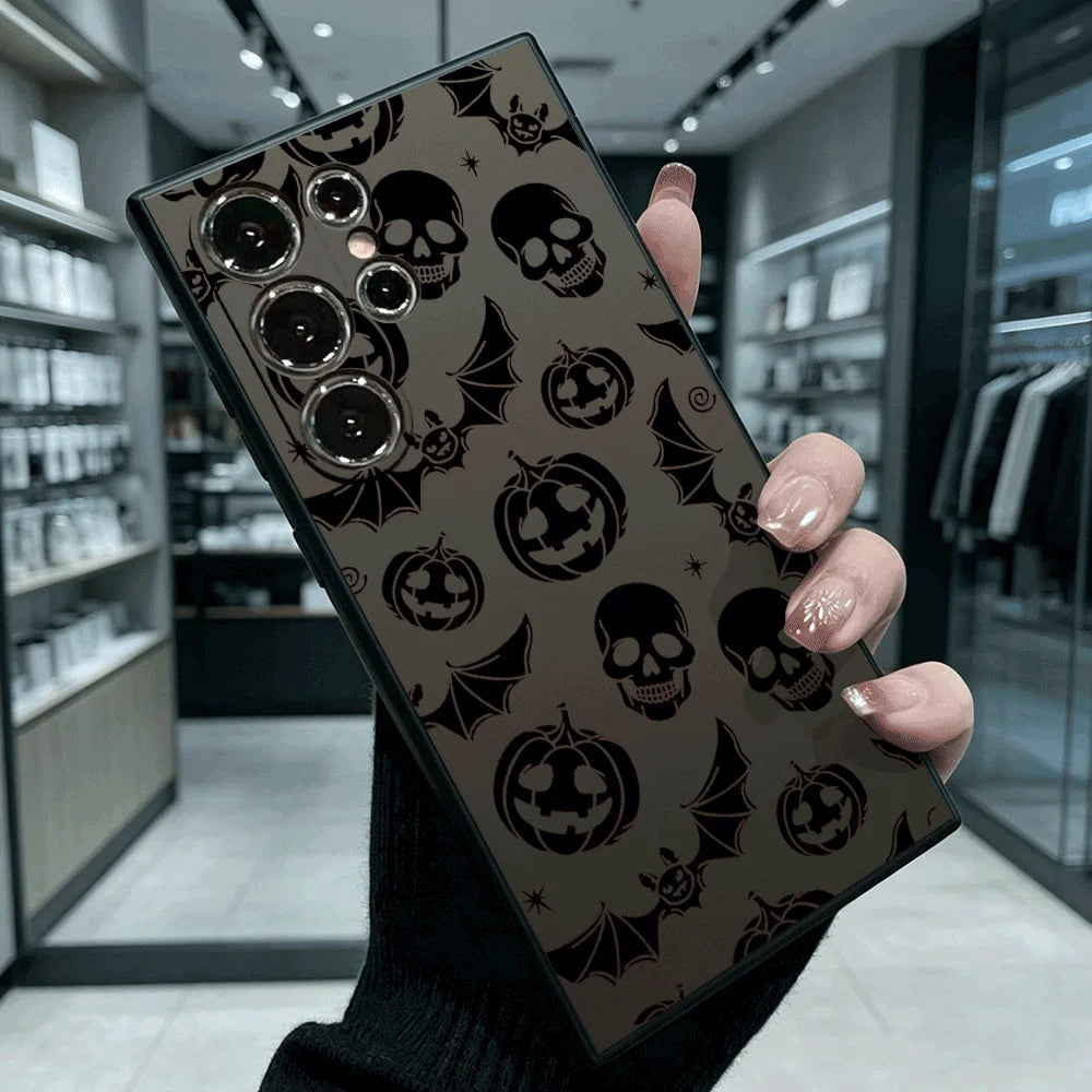 Hand hält schwarze Samsung-Hülle mit Halloween-Muster aus Totenköpfen, Kürbissen und Fledermäusen, glänzende TPU-Oberfläche