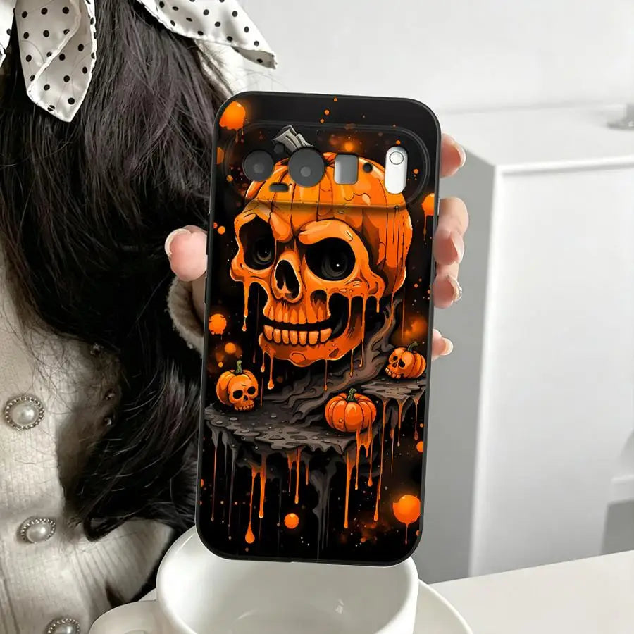 Hand hält schwarze Google-Pixel-Hülle mit orangem Totenkopf-Kürbis-Motiv und Tropf-Effekt auf dunklem Hintergrund