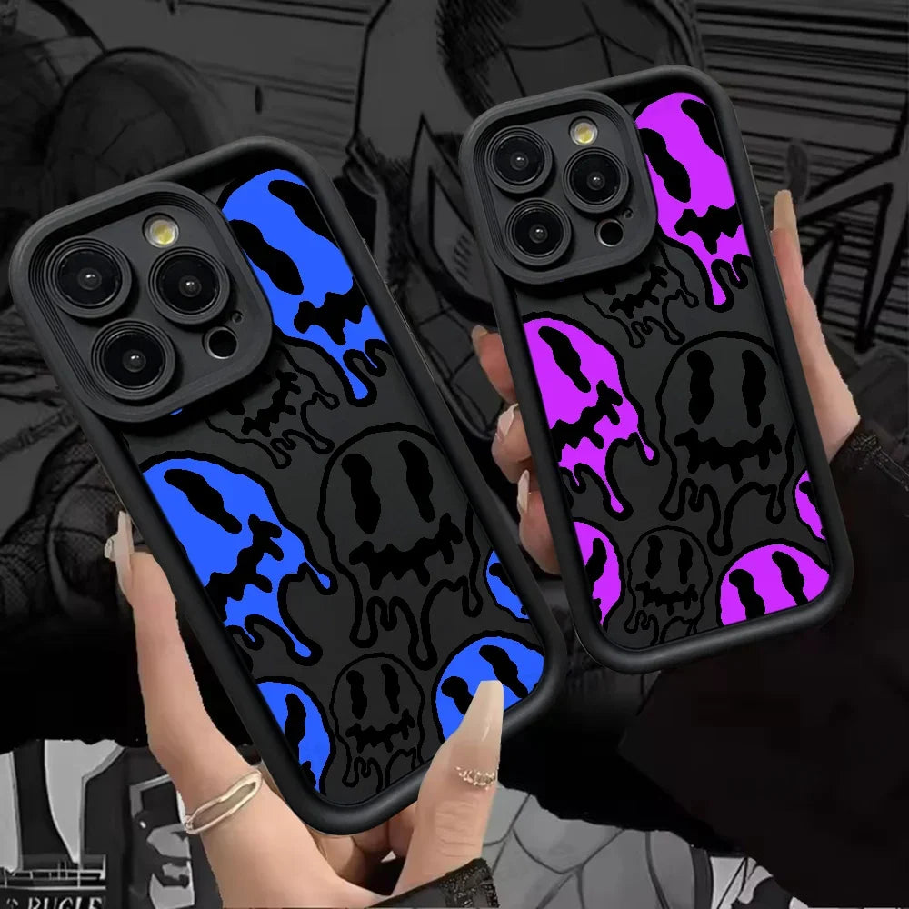 Zwei schwarze iPhone-Hüllen mit Dripping-Smiley-Motiv in Blau und Lila, in Händen gehalten