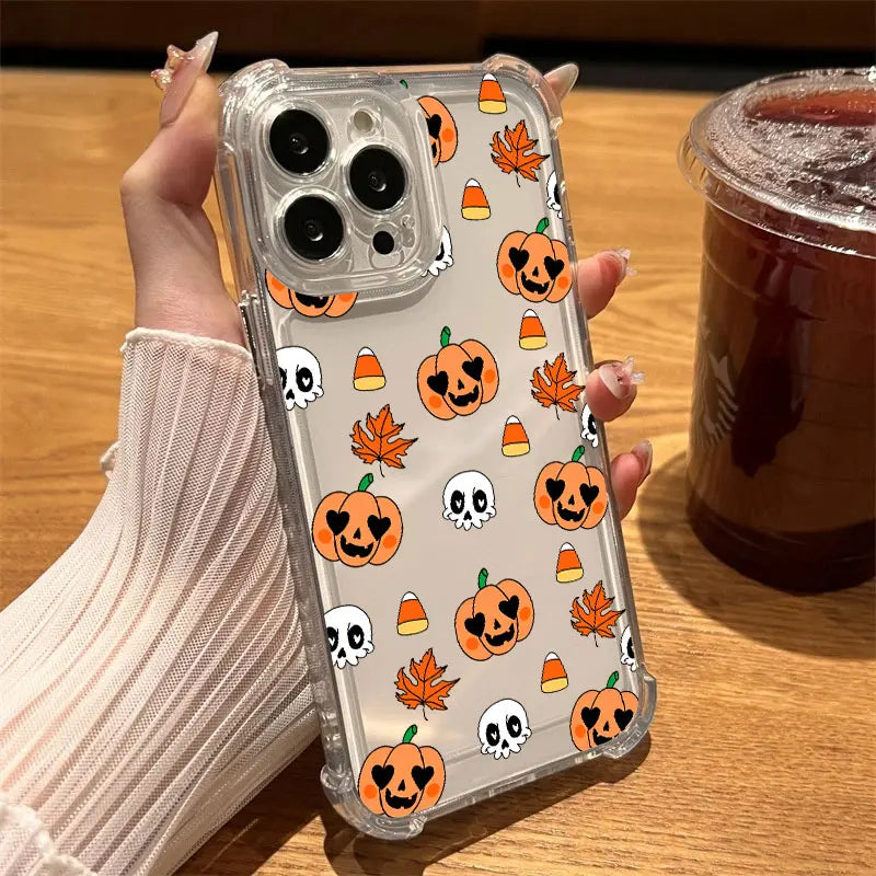 Hand hält transparente iPhone-Hülle mit orangefarbenen Kürbissen, Totenköpfen, Herbstblättern und Candy-Corn-Motiven