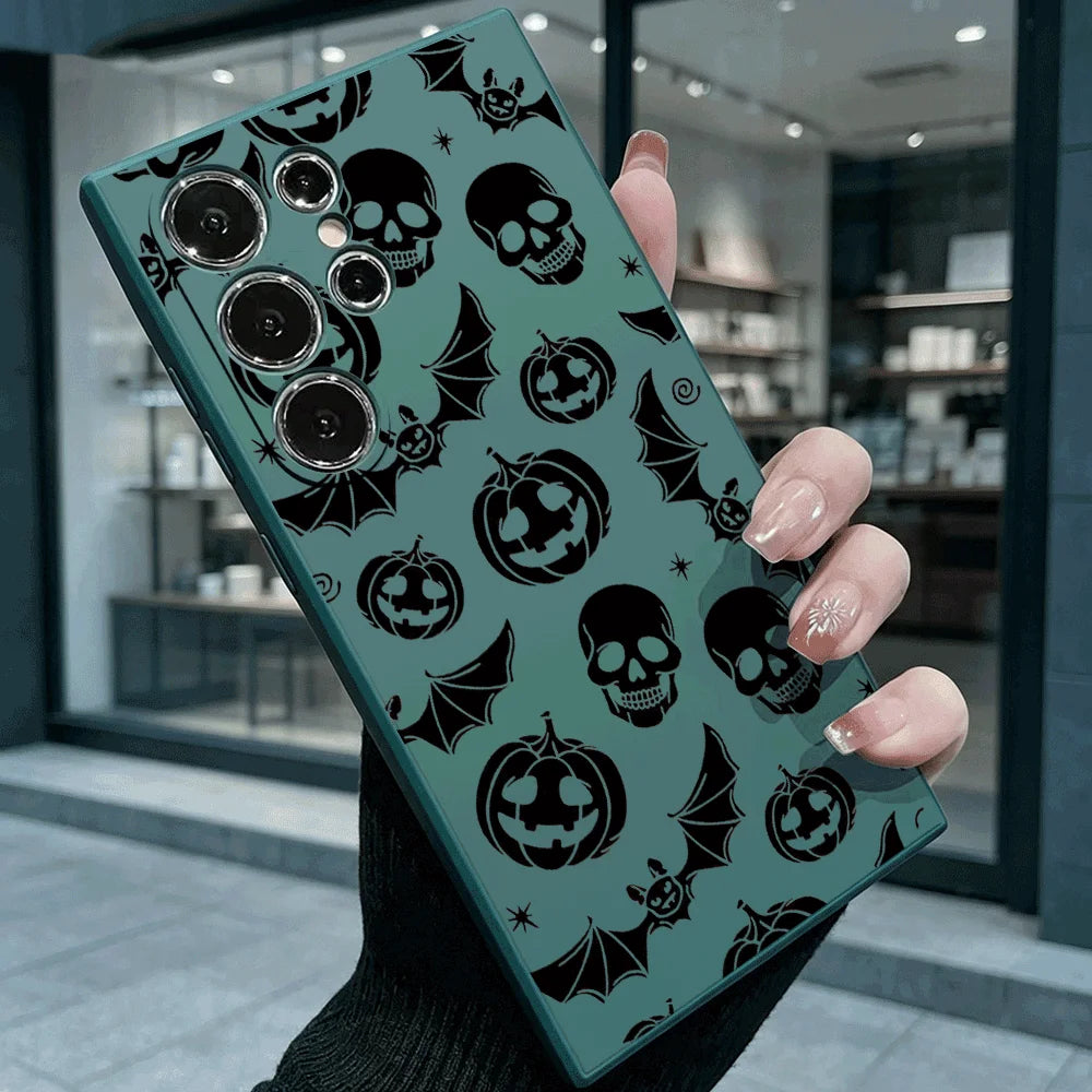 Hand hält dunkelgrüne Samsung-Hülle mit schwarzem Halloween-Muster aus Totenköpfen, Kürbissen und Fledermäusen, Rückansicht