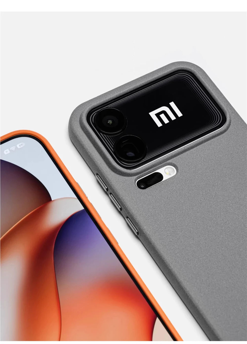 Graue matte Silikonhülle schräge Draufsicht neben orangefarbenem Smartphone-Display, Kamerabereich im Fokus