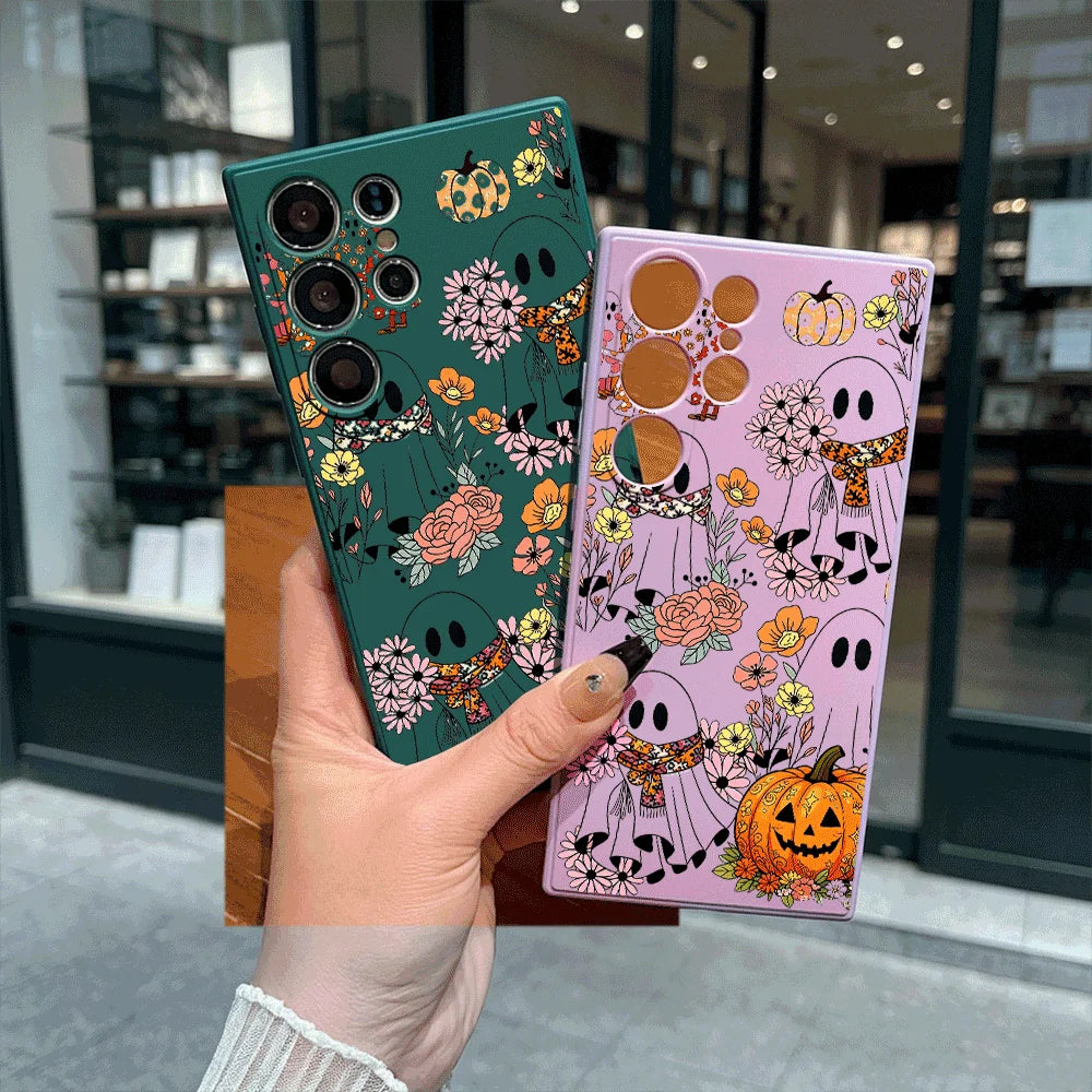 Hand hält zwei Samsung-Galaxy-Hüllen in Dunkelgrün und Rosa mit Geister-, Blumen- und Kürbis-Aufdruck