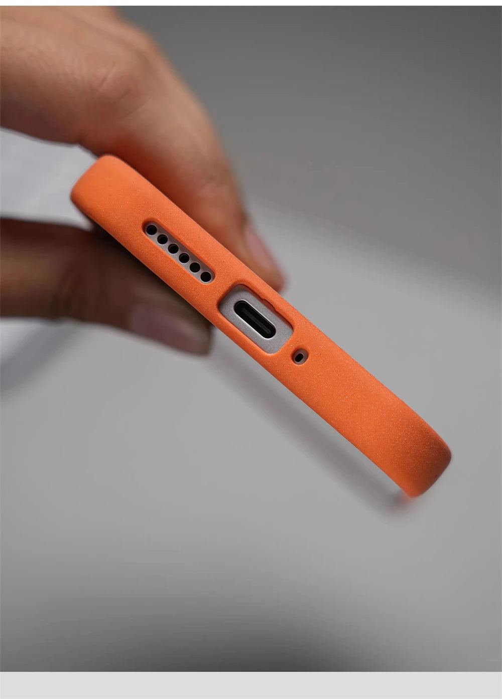 Unterseite einer orangen Silikonhülle in Nahaufnahme, USB-C-Anschluss-Ausschnitt, Lautsprecherlöcher und Mikrofon-Öffnung sic
