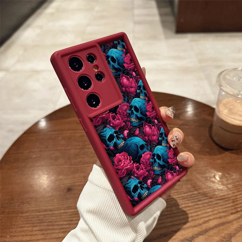 Rote Samsung-Handyhülle mit blauen Totenköpfen und pinken Blumen, Rückansicht in Hand gehalten