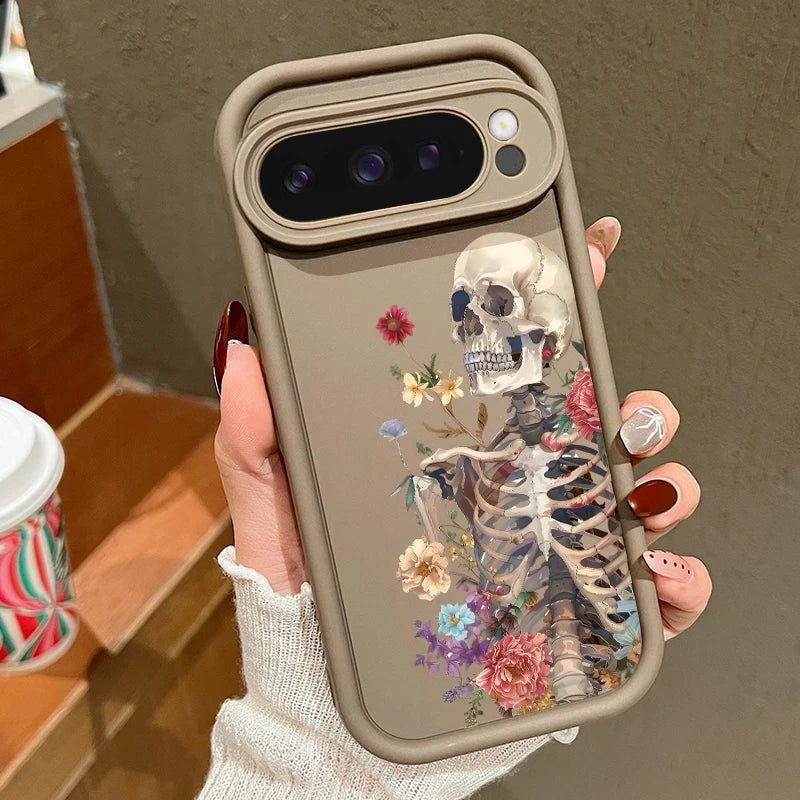 Hand hält taupefarbene Google Pixel Hülle mit botanischem Skelett-Motiv, Schädel mit bunten Blumen umrankt