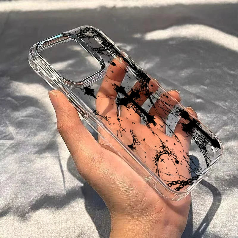 Hand hält transparente iPhone-Hülle mit schwarzem Gothic-Tintenspritzer-Muster, Innenseite sichtbar, Sonnenlicht
