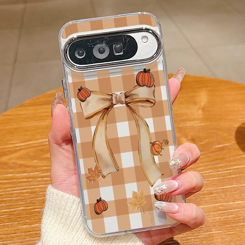 Hand hält transparente Pixel-Hülle mit beigem Karo-Muster, großer Schleife und kleinen Kürbissen sowie Herbstblättern
